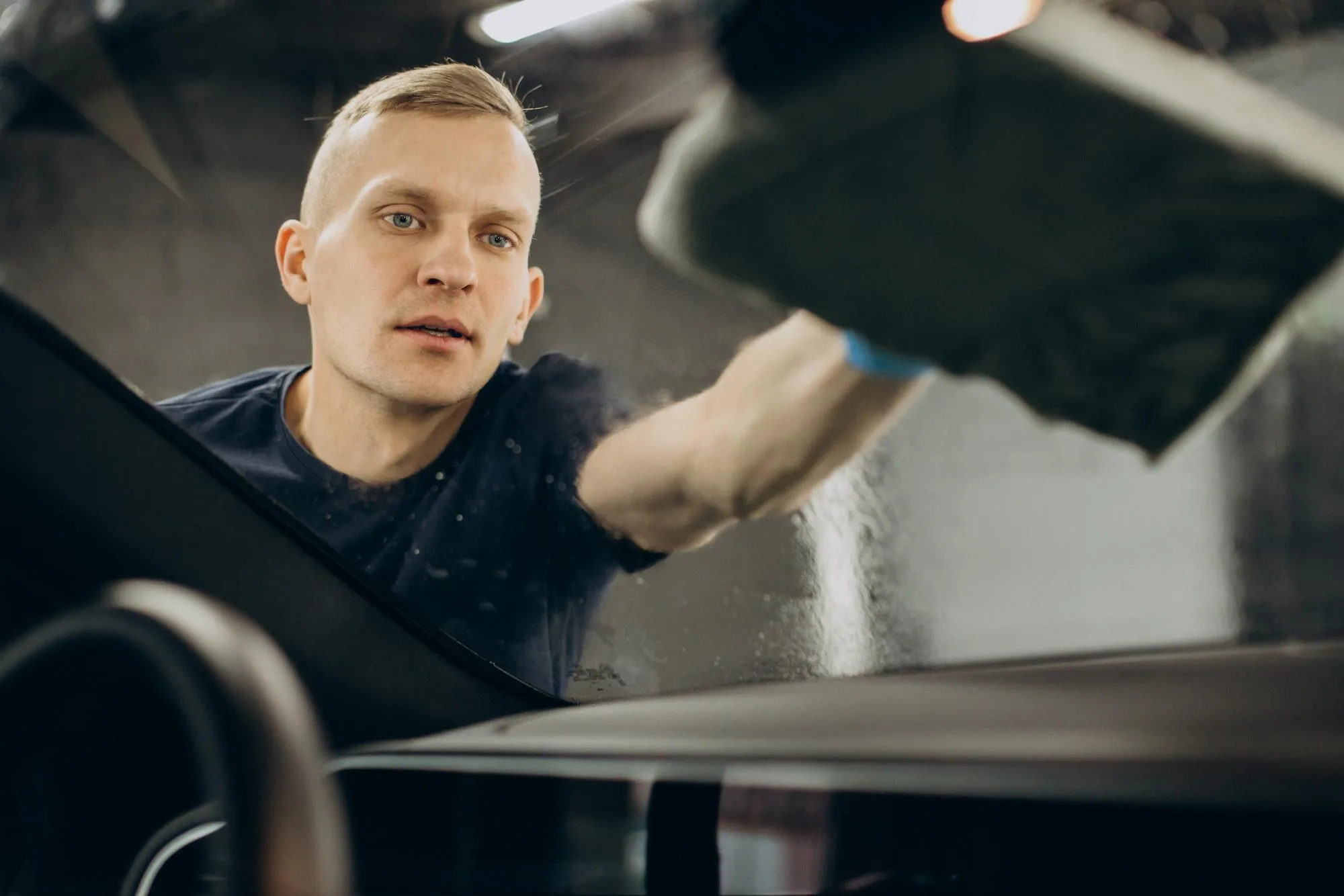 A detailer cleaning a car's windscreen